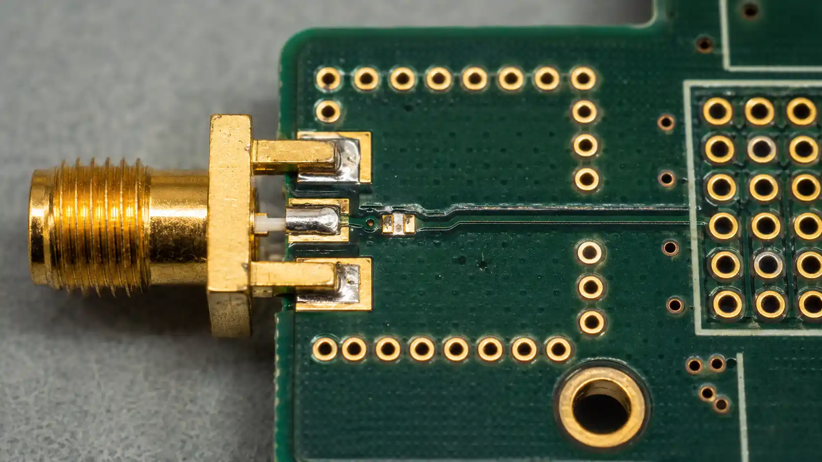 RF PCB prototype macro detail with SMA connector launch via fence ground vias controlled impedance trace and plated holes